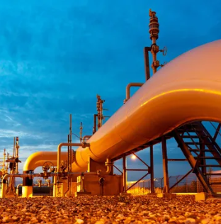 Gas pipeline and process plant floodlit at dusk
