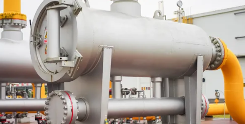 Pressure vessels and separator skids with yellow pipework on a process plant